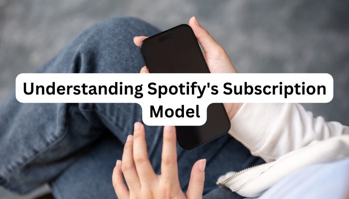 phone with logo of Spotify and man wearing jean holding the phone